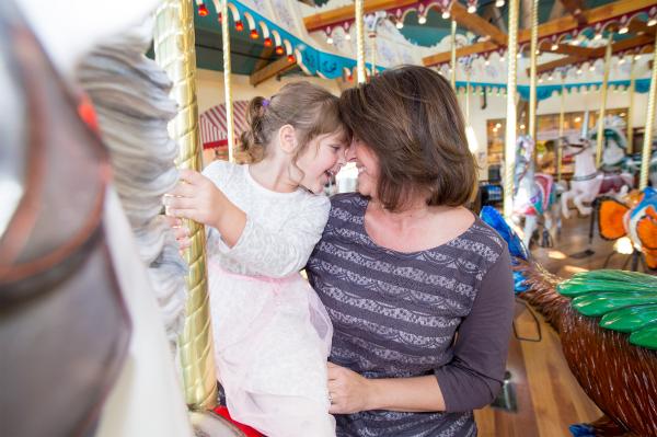mother and daughter leaning forehead to forehead on the carousel