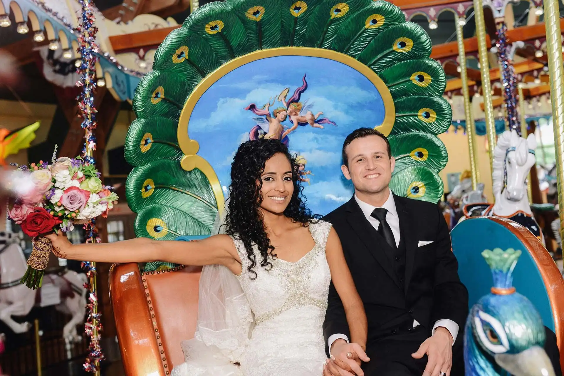 Bride and groom riding on a chariot on the carousel.