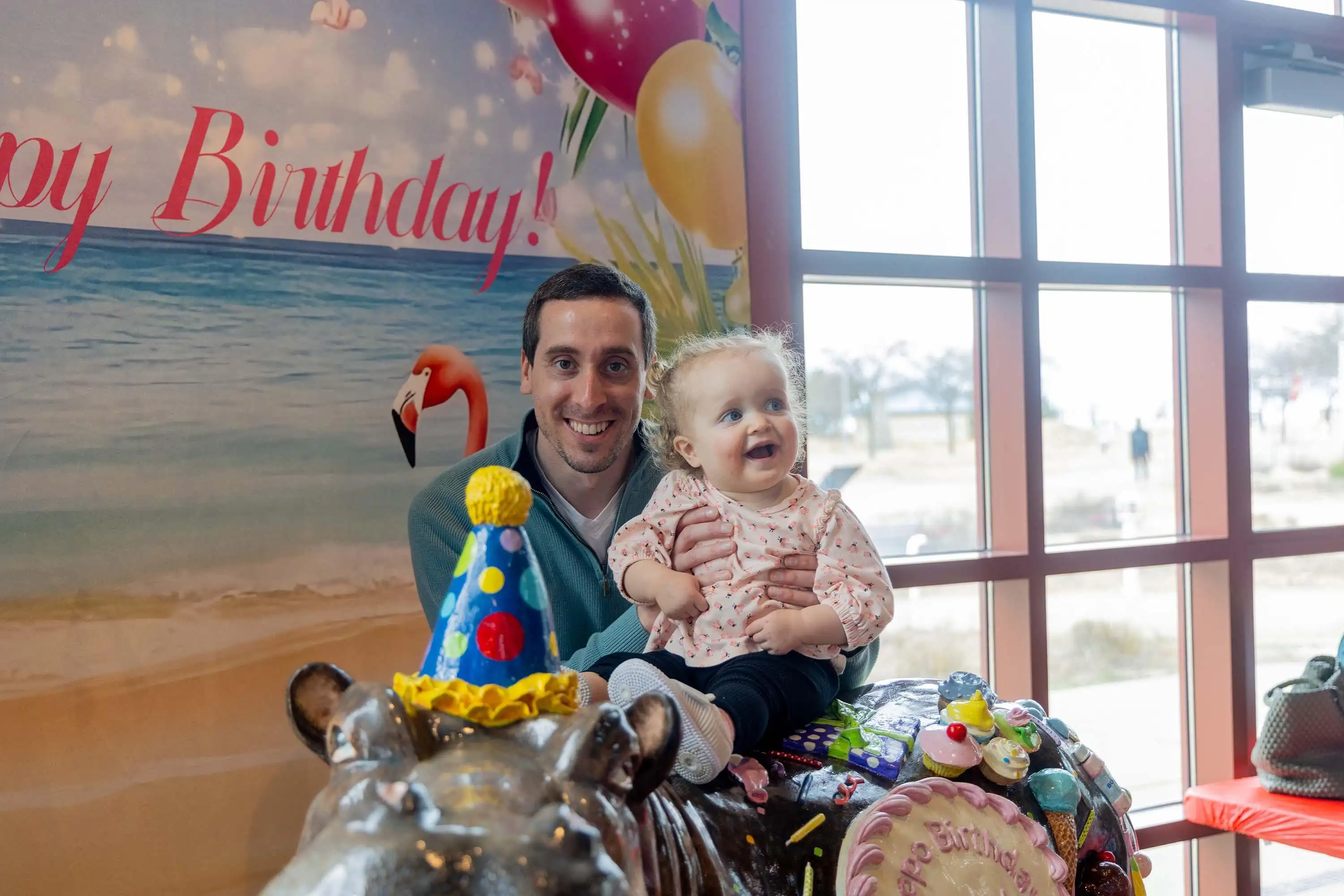 A father and child pose for a photo on the birthday hippo at the Silver Beach Carousel.