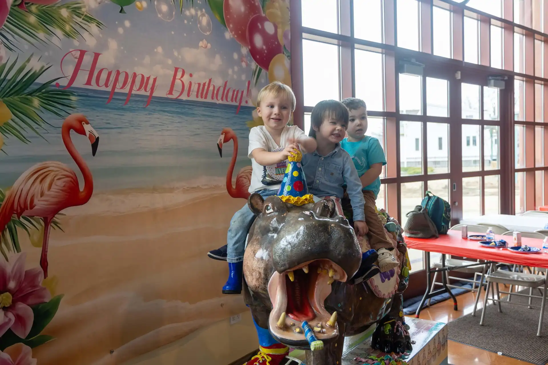 A group of children smile for a photo on the birthday hippo at the Silver Beach Carousel.