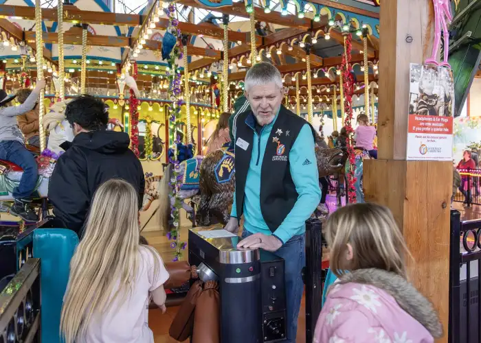 A volunteer welcomes visitors as they pass through the carousel turnstile.