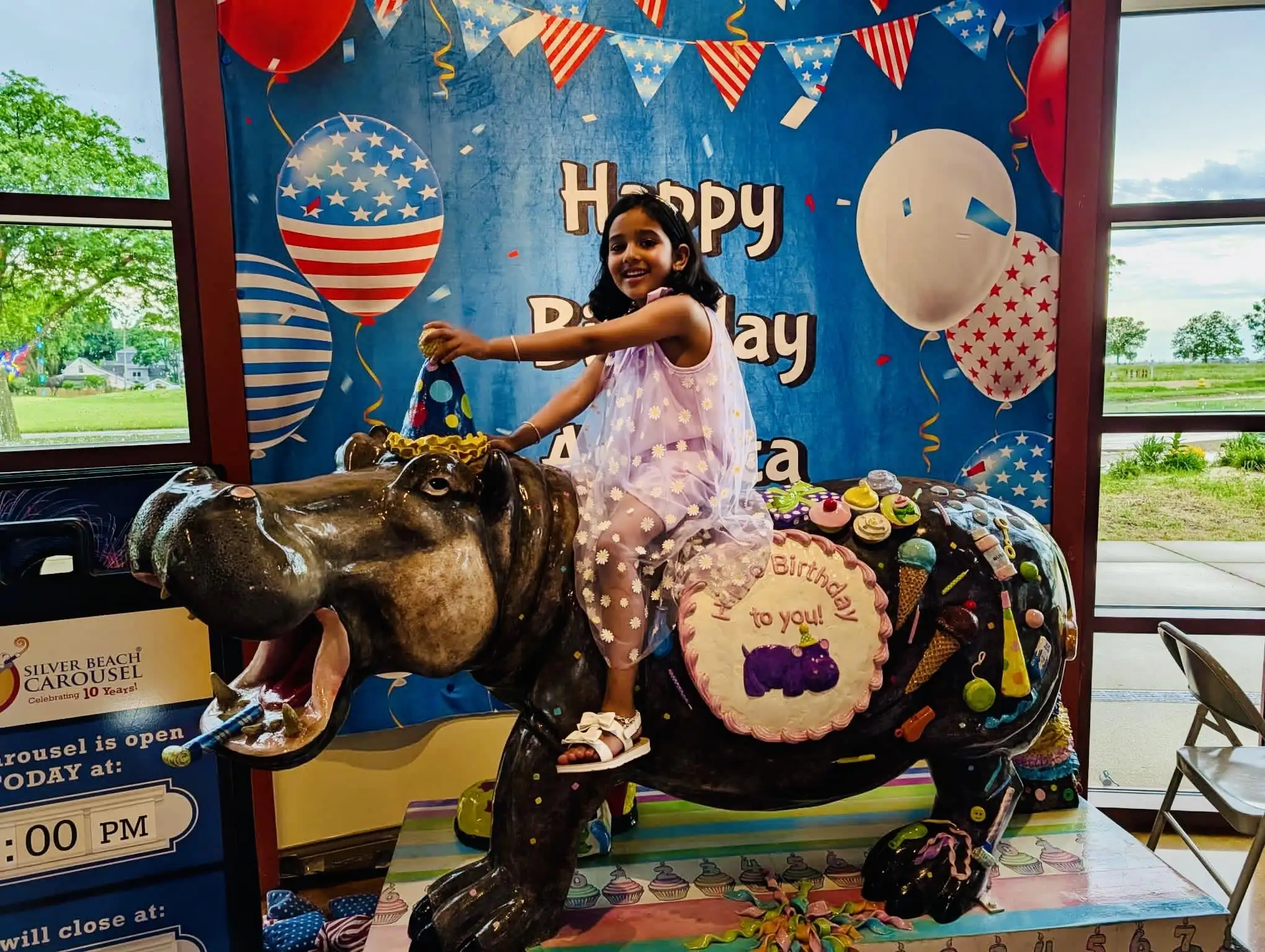 A child posing for a photo on the Birthday Hippo. 