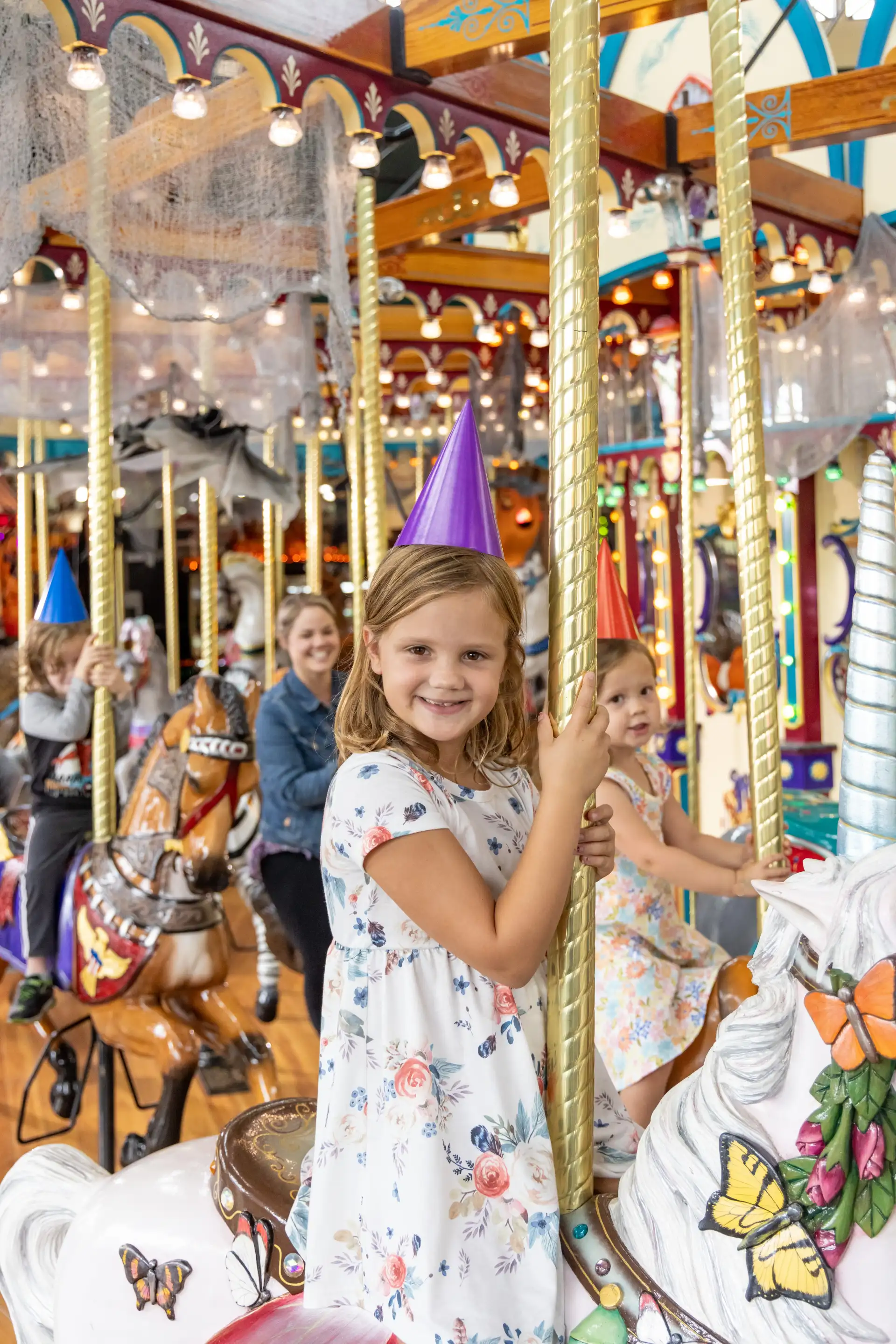 girl with party hat riding the carousel