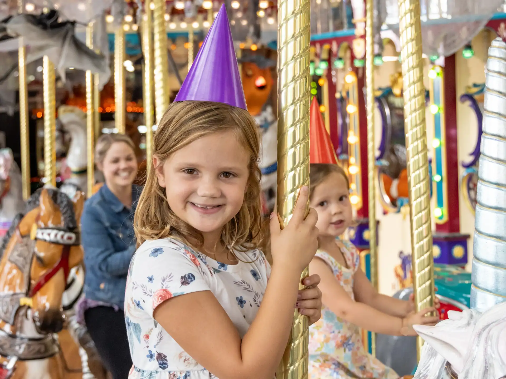 Kids with party hats riding the carousel. 